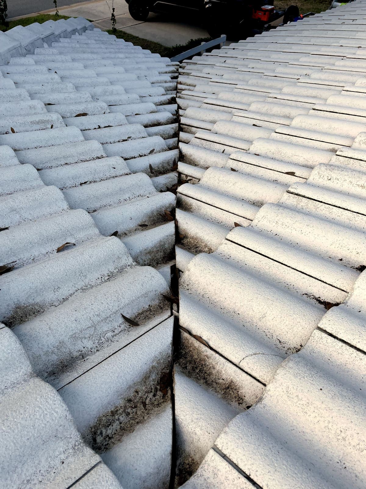 White tile roof with black algae streaks before cleaning