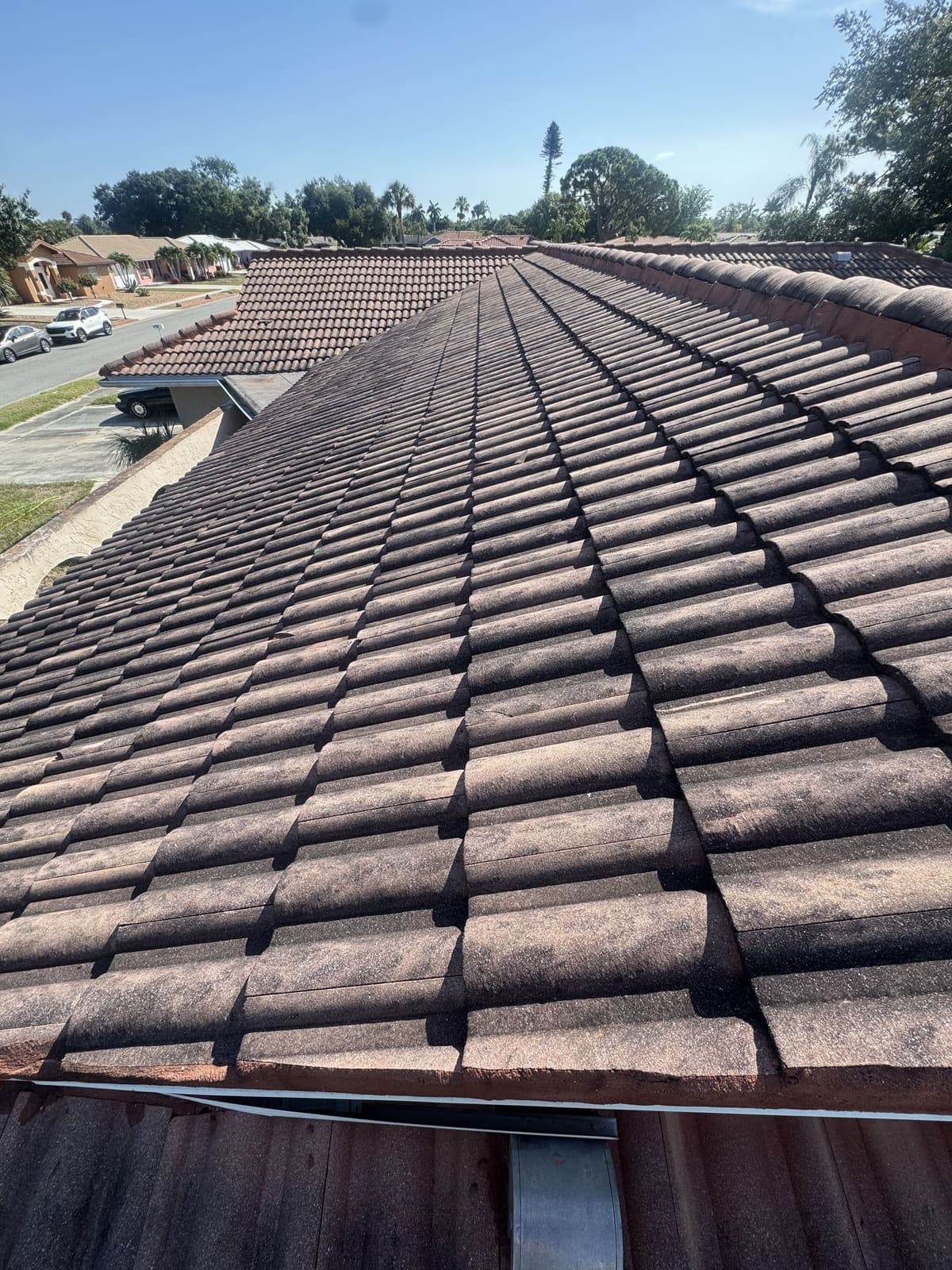 The same tile roof before cleaning, darkened with dirt and algae