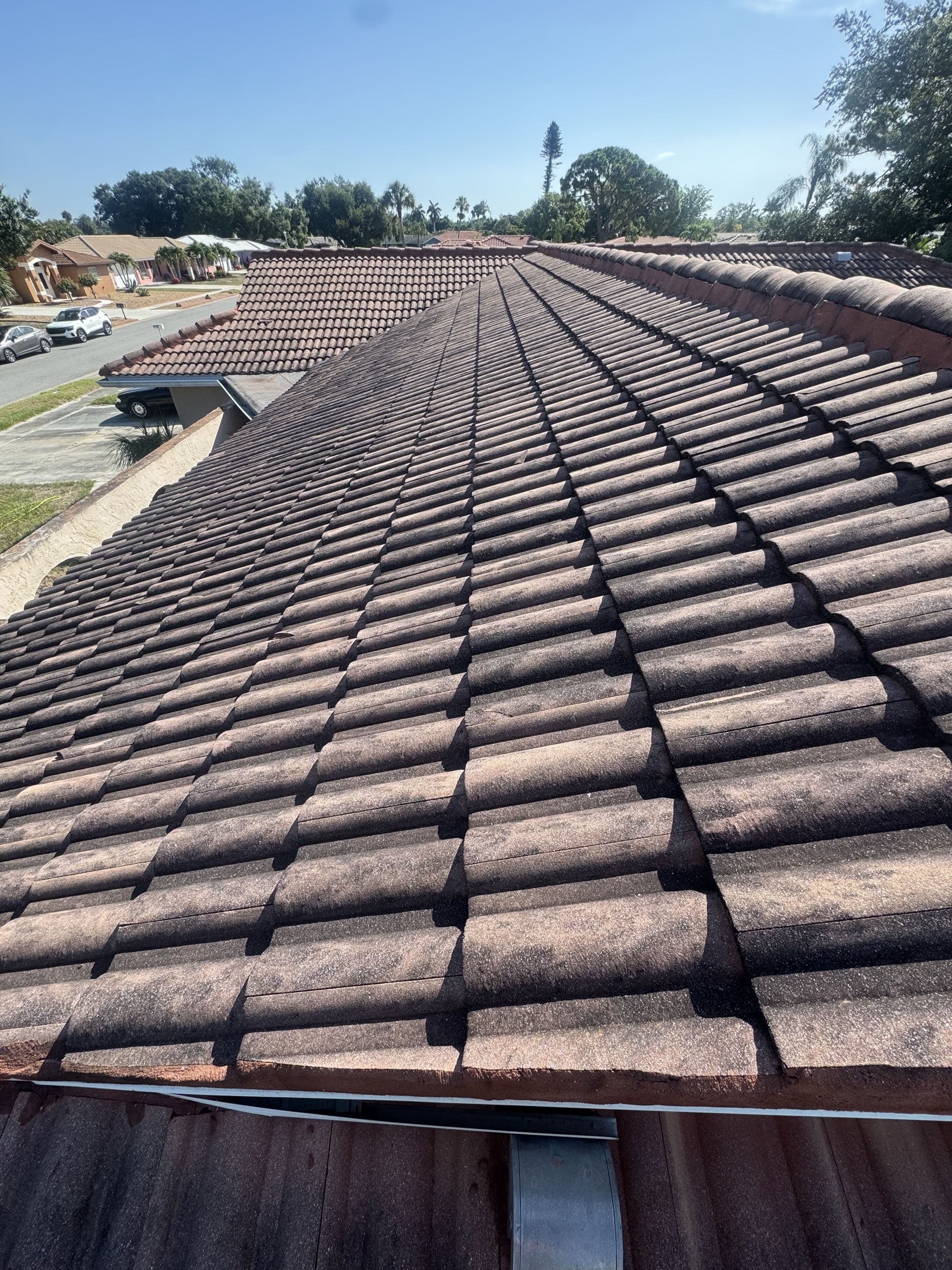 The same tile roof before cleaning, darkened with dirt and algae